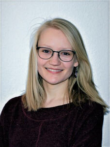 Nora Winkler mit Brille und langem blondem Haar vor hellem Hintergrund.